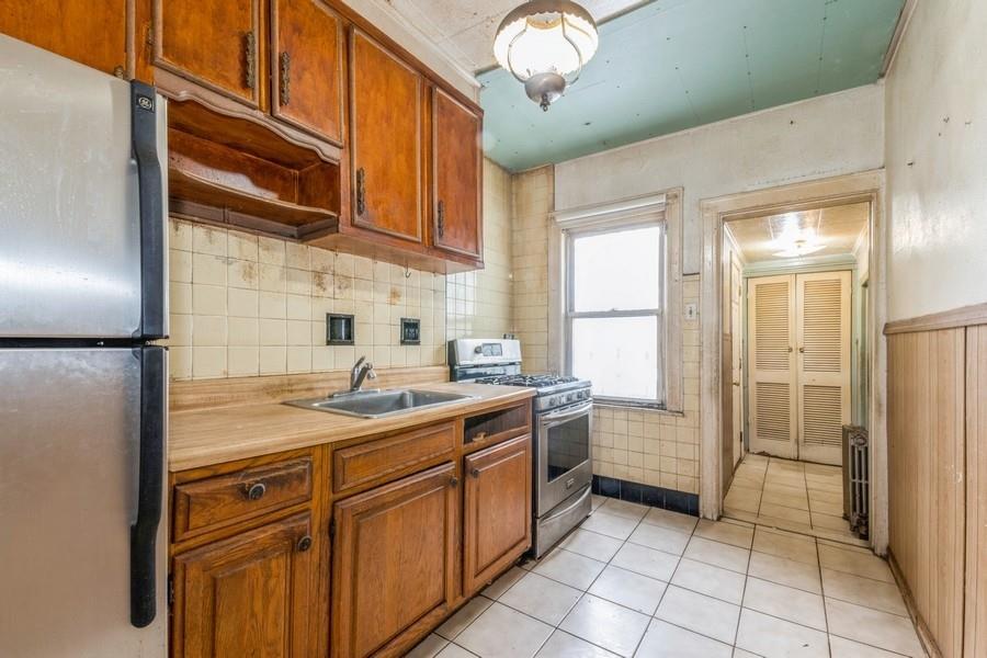 Kitchen with light countertops, appliances with stainless steel finishes, brown cabinetry, and a sink