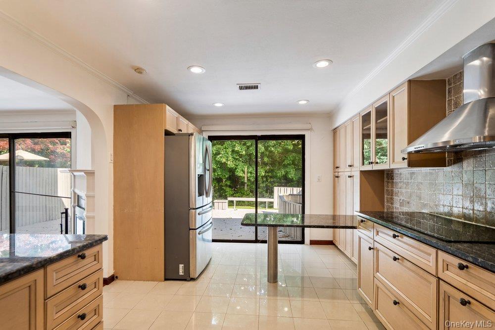 Kitchen featuring light-toned cabinetry, dark granite countertops, stainless steel appliances, and a tiled backsplash