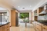 Kitchen featuring light-toned cabinetry, dark granite countertops, stainless steel appliances, and a tiled backsplash