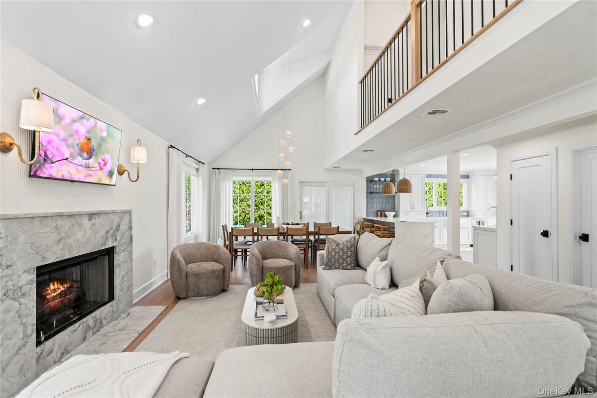 Living area featuring a premium fireplace, high vaulted ceiling, wood finished floors, and recessed lighting