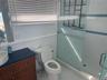 Bathroom featuring a stall shower, toilet, tile patterned flooring, vanity, and a wainscoted wall