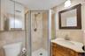 Bathroom featuring a corner shower with a glass enclosure, a vanity with an ornate wood-finish base and light-colored countertop, and a decorative fra