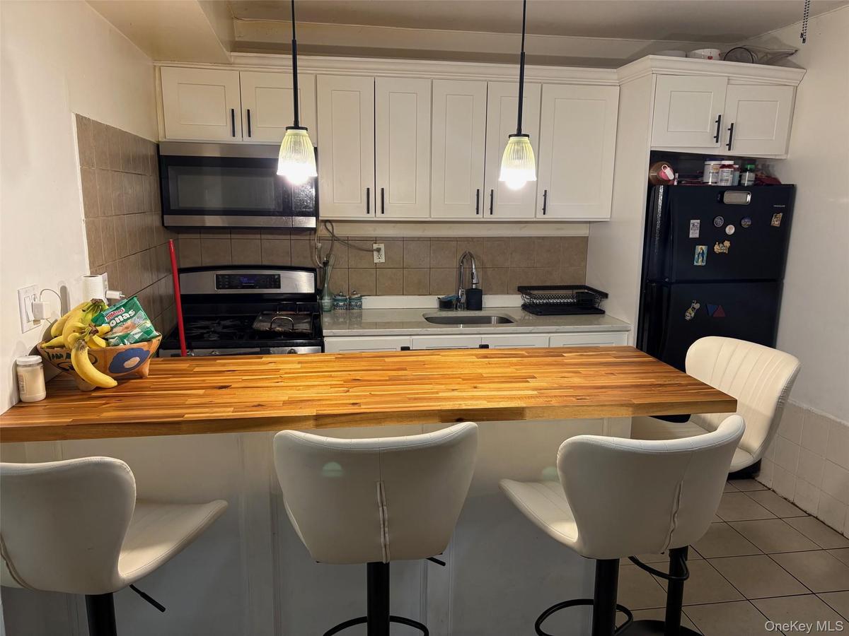 Kitchen with a kitchen breakfast bar, stainless steel appliances, butcher block countertops, and white cabinetry