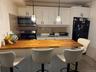 Kitchen with a kitchen breakfast bar, stainless steel appliances, butcher block countertops, and white cabinetry
