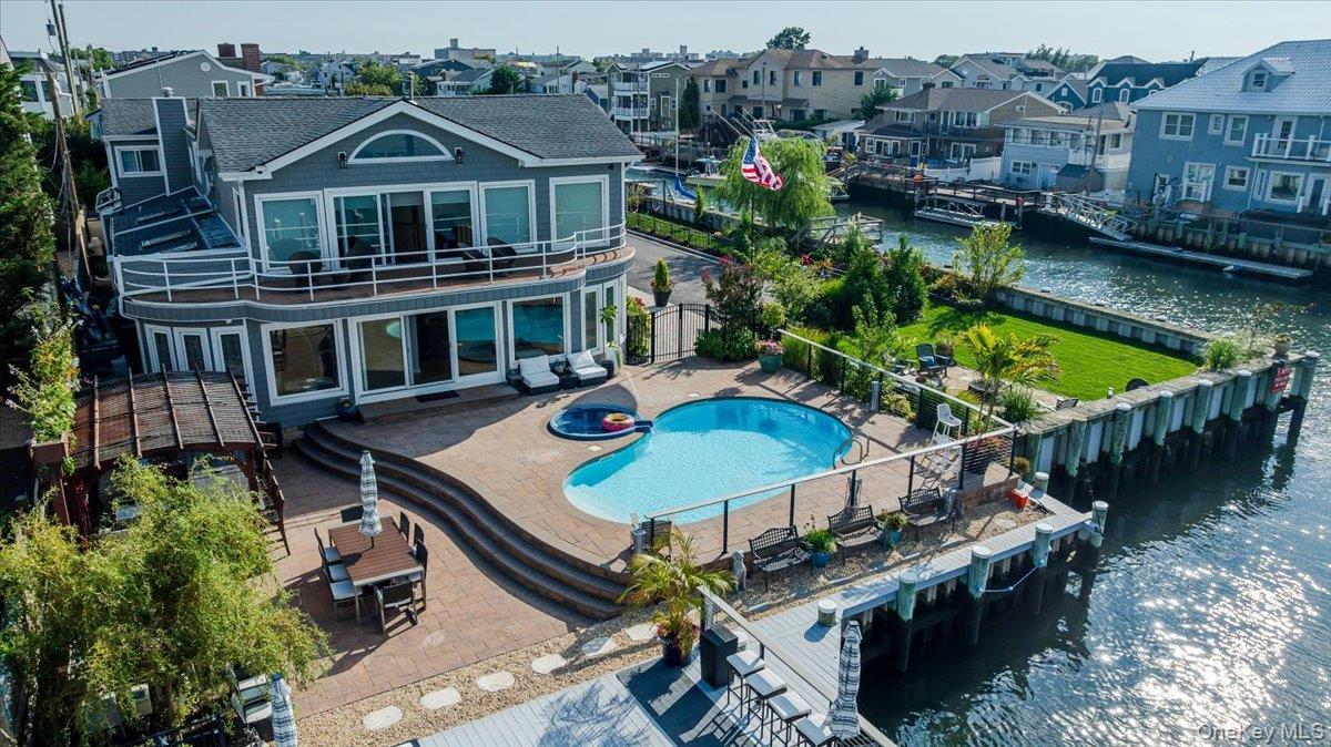 Rear view of house with a water view, a patio, a residential view, a fenced backyard, and a gate