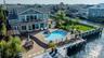 Rear view of house with a water view, a patio, a residential view, a fenced backyard, and a gate