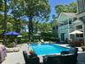 Swimming pool featuring outdoor dining area, a balcony, area for grilling, a patio, and view of wooded area