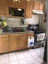 Kitchen featuring stainless steel gas range, light tile patterned flooring, dark countertops, and brown cabinetry