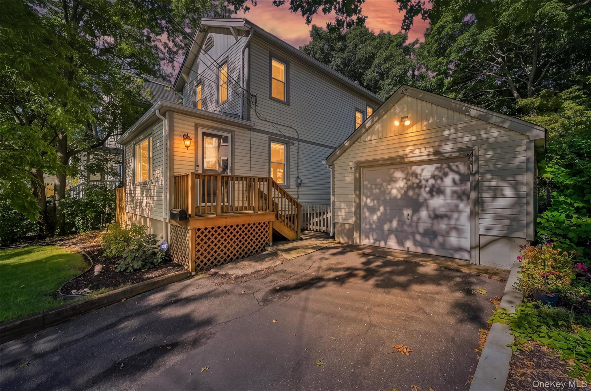 Twilight view of front. Including the detached garage and driveway