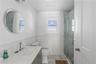 Bathroom with vanity, wooden walls, a shower with door, and toilet