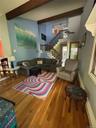 Front Living area featuring high ceilings with exposed wood beams, hardwood flooring, and a multi-level staircase with wood handrails and black metal