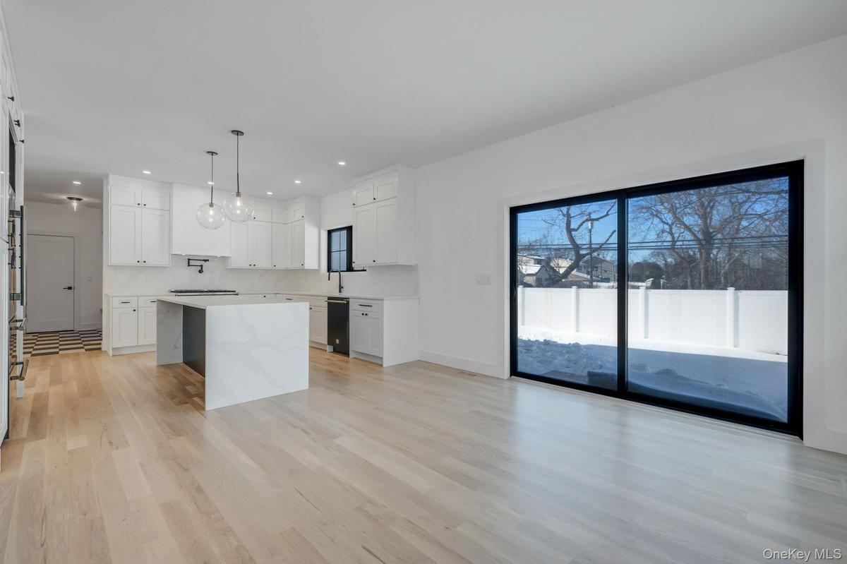 Bright dining space positioned beside kitchen and living room featuring wet bar and large glass sliders, offering great natural light and easy access
