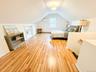 Bedroom with vaulted ceiling, a wall mounted AC, and light wood-type flooring