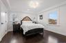 Bedroom featuring crown molding, dark wood-style floors, a chandelier, a raised ceiling, and recessed lighting