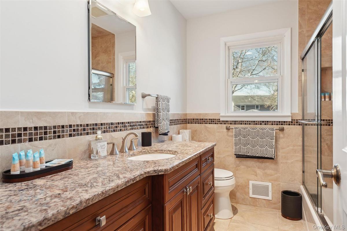 Bathroom featuring vanity, tile walls, tile patterned floors, and toilet