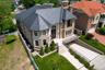 View of front of property with concrete driveway, an attached garage, stone siding, a high end roof, and a residential view