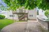 Expansive paver patio featuring a built-in stone veneer outdoor kitchen prep area
