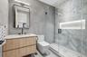 Bathroom with vanity, tile walls, and a marble finish shower