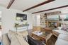 Living room with wood finished floors, a fireplace, beamed ceiling, and built in shelves