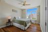 Bedroom 3 featuring wood-finish flooring, a contemporary ceiling fan, and a large window offering urban building views
