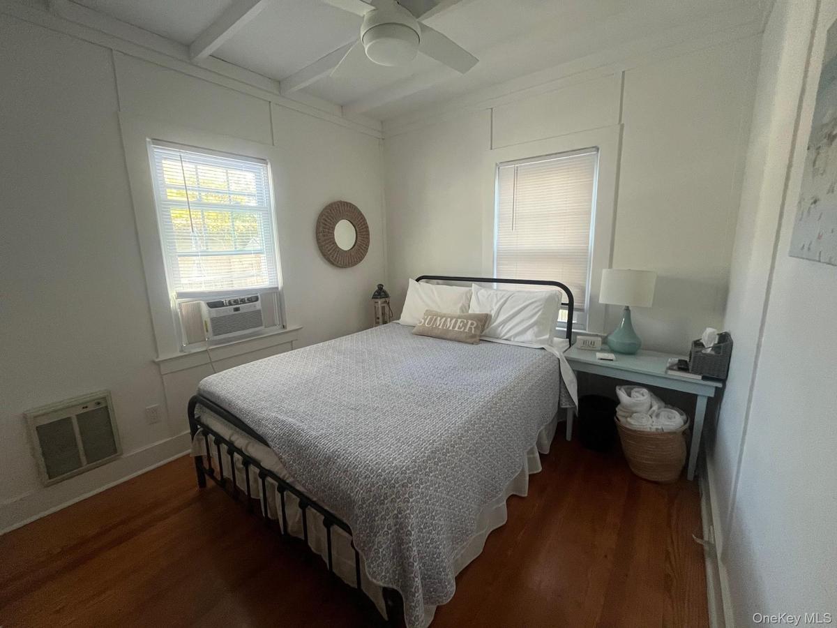 Bedroom featuring dark wood-style flooring, beam ceiling, ceiling fan, and cooling unit