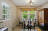 Kitchen dining area featuring a glass-paned door, double windows, tiled flooring, built-in baseboard heating, and a flush-mount ceiling light fixture