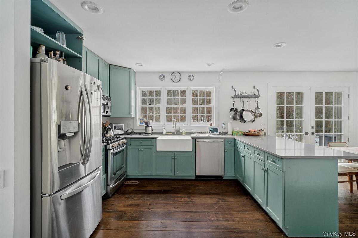 Kitchen featuring green cabinets, stainless steel appliances, a peninsula, french doors, and dark wood-style flooring