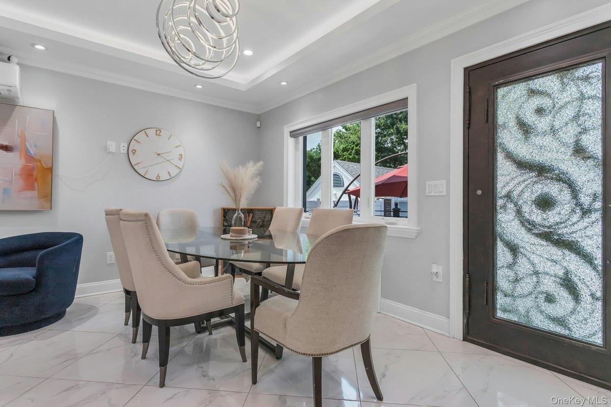 Dining area featuring a contemporary chandelier, recessed lighting, crown molding, white tile flooring, and a decorative glass iron entry door