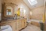 Bathroom featuring tile walls, a skylight, tiled shower / bath, double vanity, and vaulted ceiling