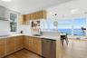 Kitchen with wall chimney exhaust hood, stainless steel dishwasher, pendant lighting, light wood-type flooring, and decorative backsplash