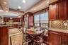 Kitchen with light stone counters, backsplash, reddish brown cabinets, stainless steel appliances, and recessed lighting