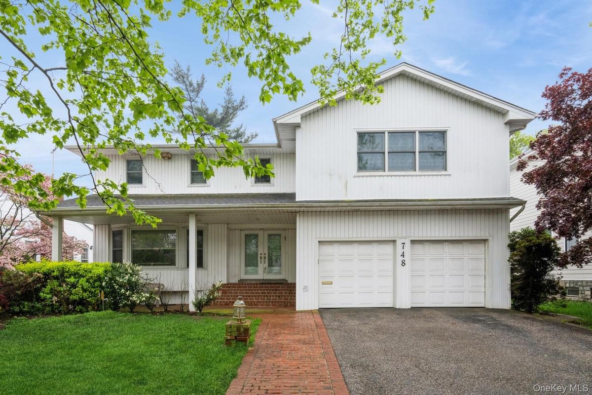 Traditional-style home with french doors, asphalt driveway, an attached garage, and a front lawn