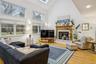 Living area featuring high vaulted ceiling, a skylight, a fireplace, wood finished floors, and recessed lighting