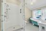 Bathroom with vaulted ceiling, a freestanding bath, a stall shower, and light tile patterned flooring