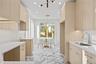 Kitchen featuring light brown cabinetry, modern cabinets, recessed lighting, pendant lighting, and light stone countertops