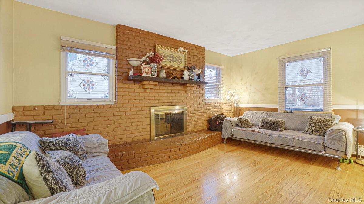 Living room featuring a wainscoted wall, a brick fireplace, and wood-type flooring