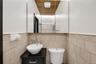Bathroom featuring a vessel sink with chrome fixtures, a dark wood-finish vanity with drawer, and light-toned tiled walls with decorative banding
