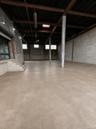 Expansive open-concept space featuring exposed structural beams, a concrete floor, and block walls