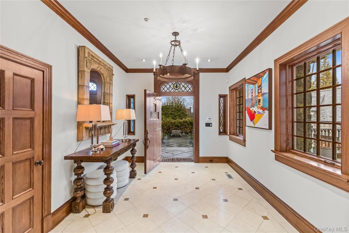 Foyer featuring suspended lighting, marble floors, and detailed molding.