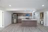 Kitchen with stainless steel fridge with ice dispenser, an island with sink, light wood-type flooring, tasteful backsplash, and recessed lighting
