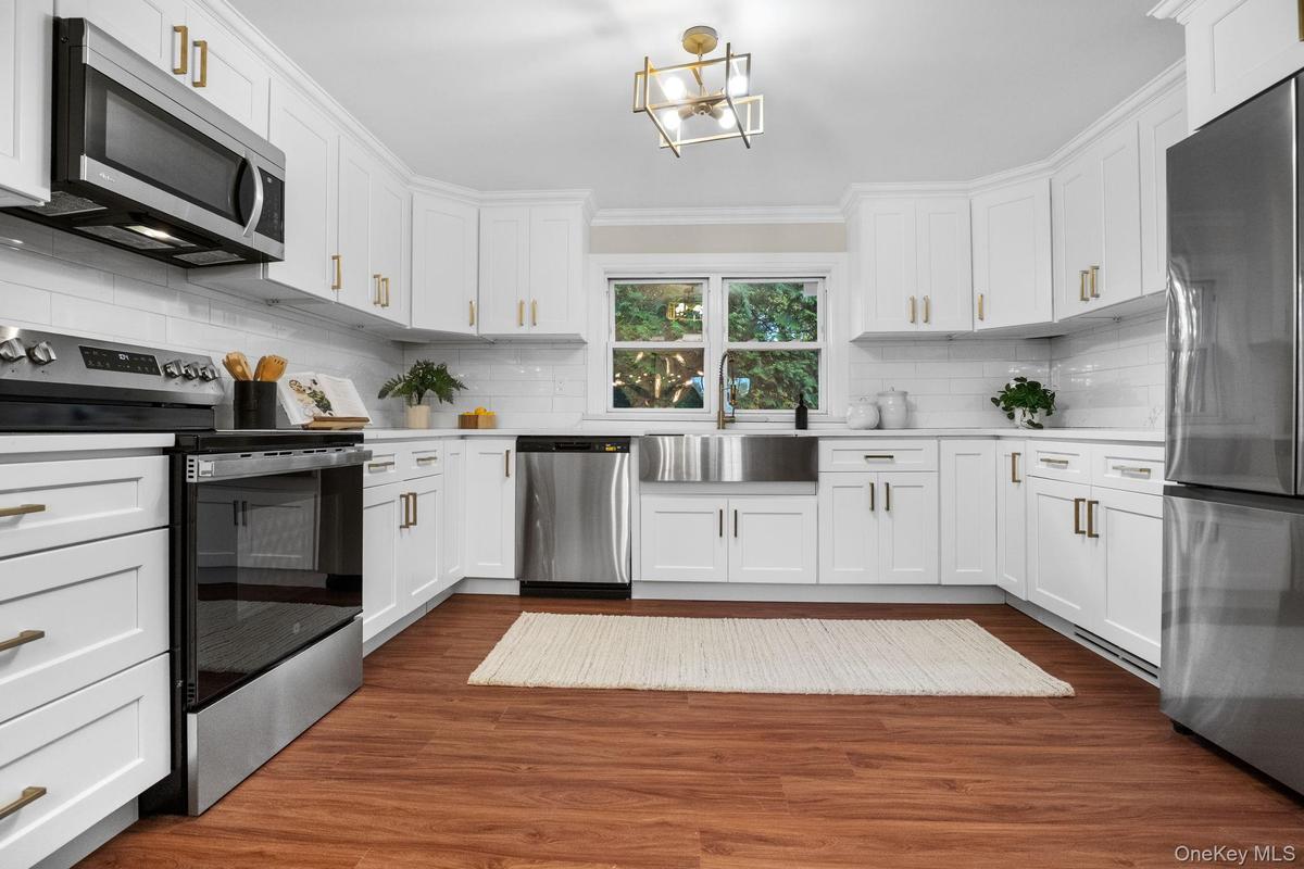 Bright and spacious kitchen with custom shaker cabinets, gold hardware, and a farmhouse sink for a perfect blend of elegance and function.