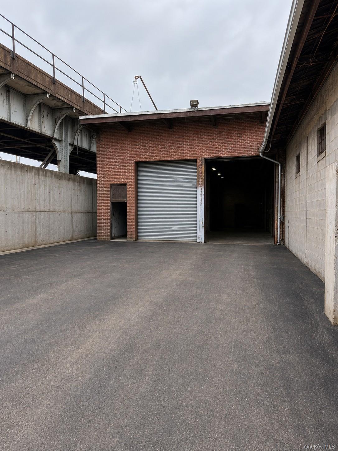 Brick exterior building featuring two roll-up doors and an expansive paved lot