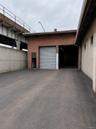 Brick exterior building featuring two roll-up doors and an expansive paved lot