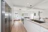 Kitchen with appliances with stainless steel finishes, light wood-style flooring, beamed ceiling, white cabinetry, and recessed lighting