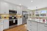 Kitchen featuring appliances with stainless steel finishes, light stone countertops, white cabinetry, and recessed lighting