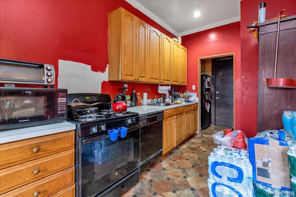 Kitchen with ornamental molding and black appliances
