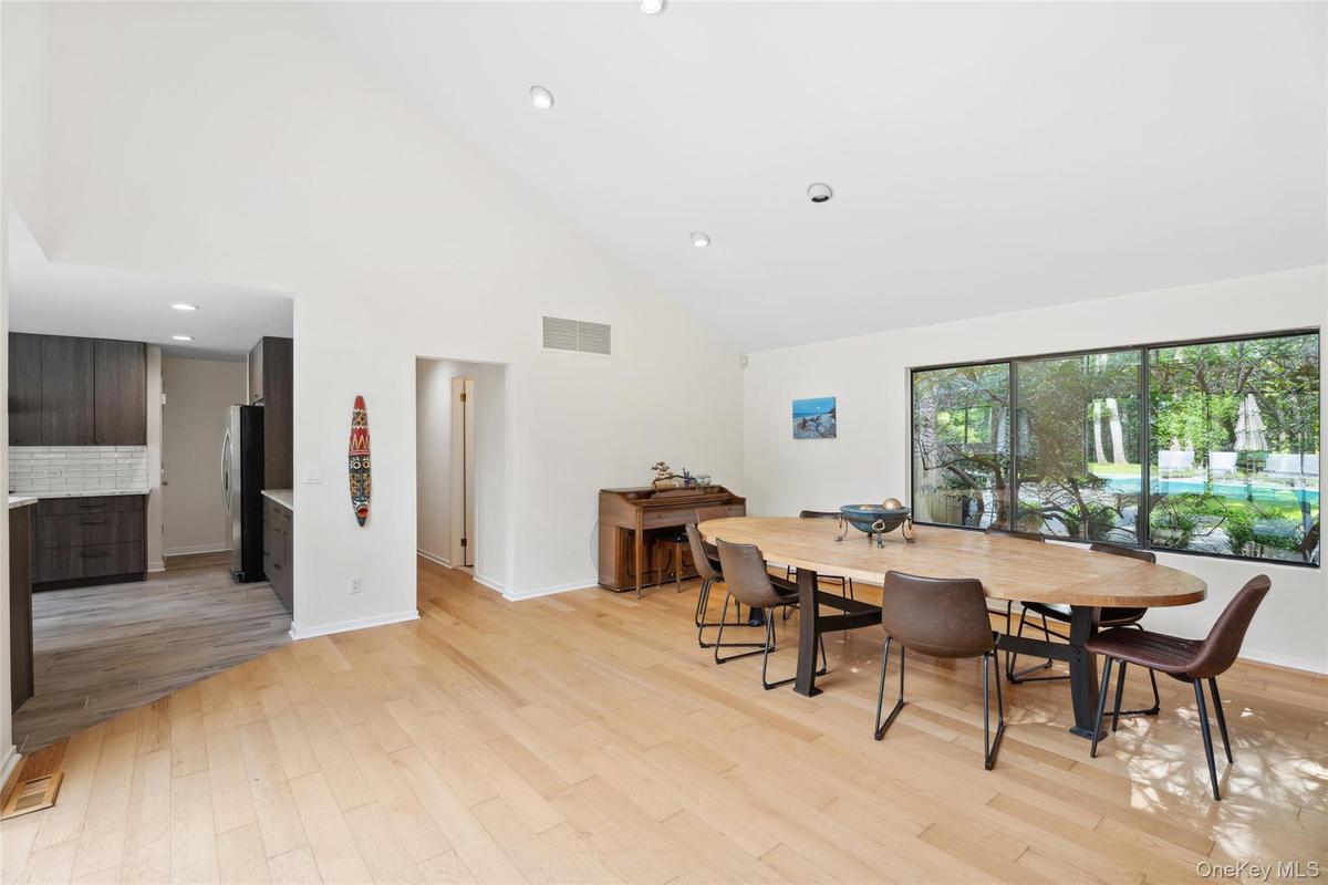Dining space featuring high vaulted ceiling, light wood-style flooring, and recessed lighting