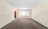 Carpeted spare room featuring arched walkways and radiator