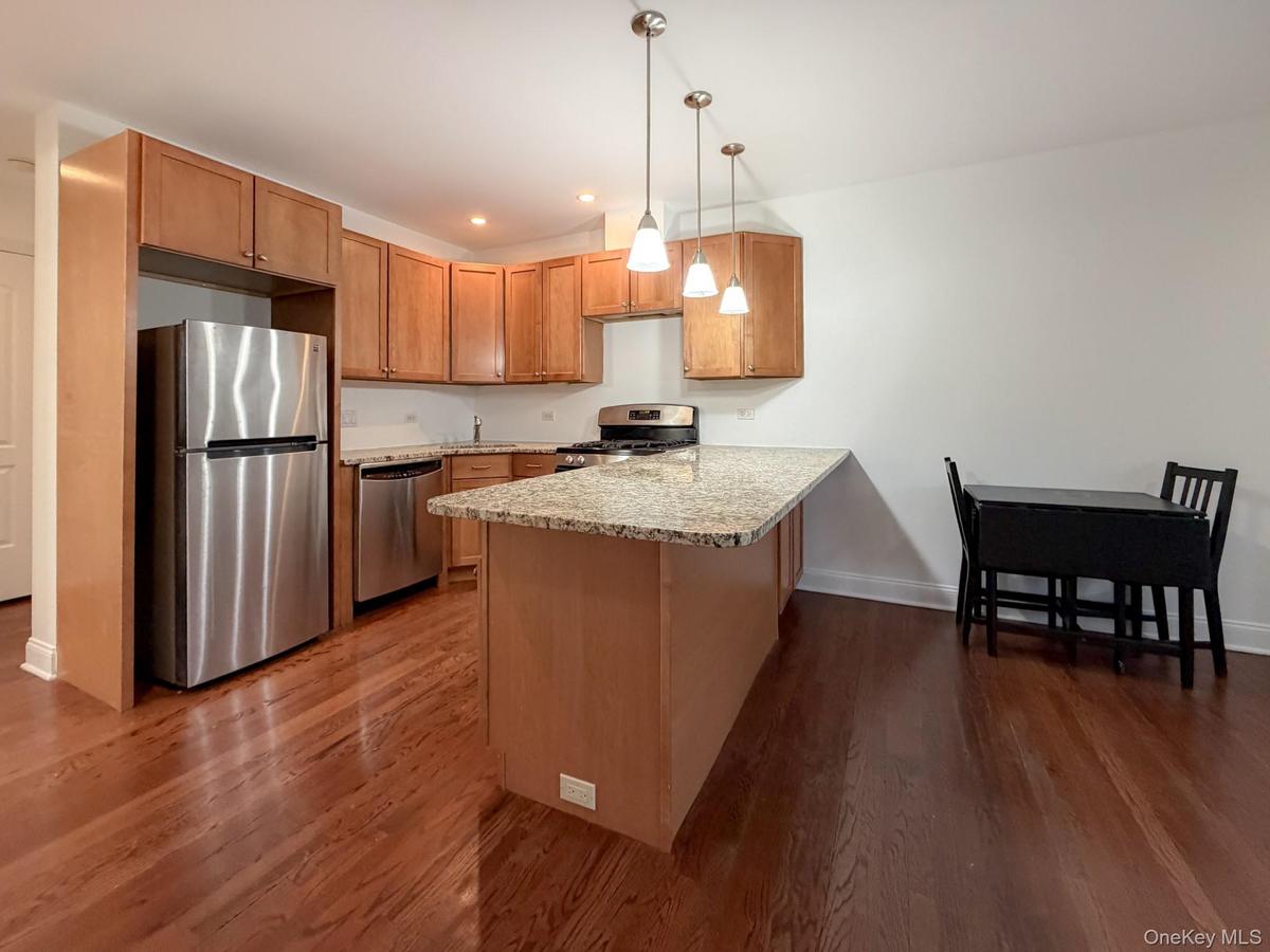 Kitchen with a peninsula, stainless steel appliances, pendant lighting, light stone countertops, and recessed lighting