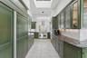 Kitchen featuring decorative backsplash, appliances with stainless steel finishes, a skylight, light tile patterned floors, and dark stone countertops